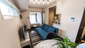 Un espace de vie compact comprenant un canapé, une petite table, un téléviseur et une plante.