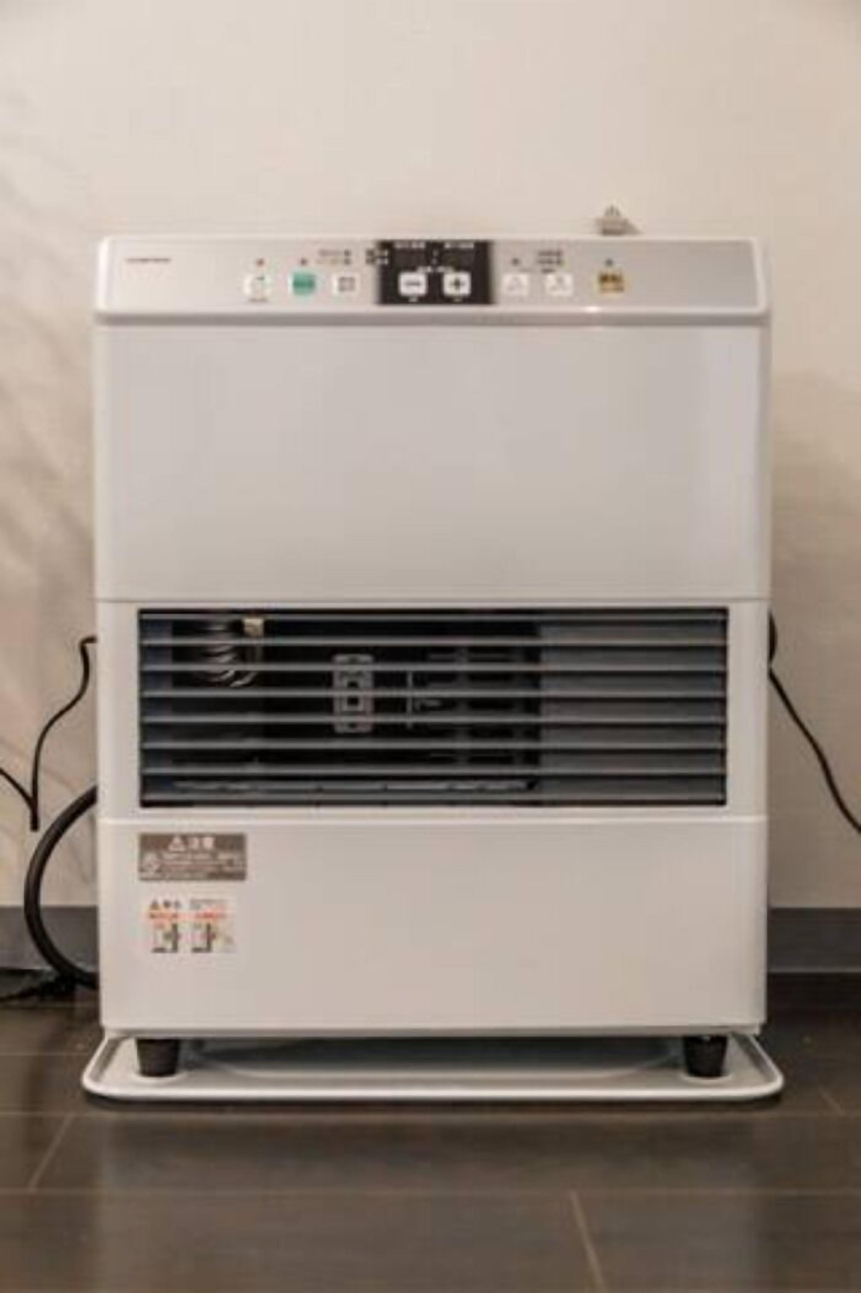 Un climatiseur portatif blanc, doté d’un panneau de commande, d’une grille d’aération et d’étiquettes de sécurité.