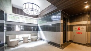Un hall d’entrée moderne avec un espace salon, un système d’alarme incendie et une vue à travers le mur de verre.