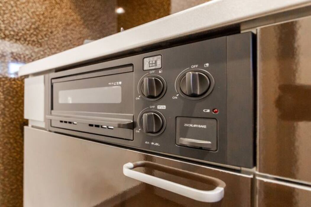 A kitchen with a built-in oven and microwave, a handle for opening the oven, and a control panel with various buttons and a display.