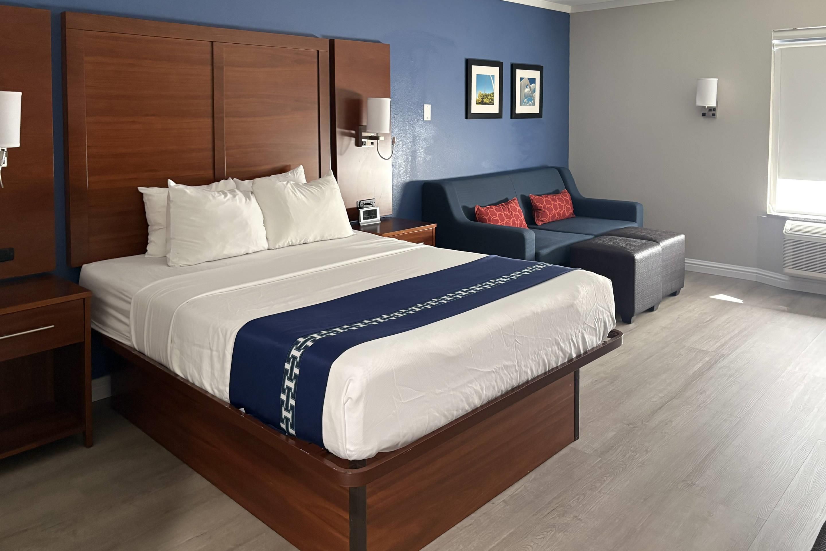 A hotel room with a large bed, a desk, a chair, and a small table.