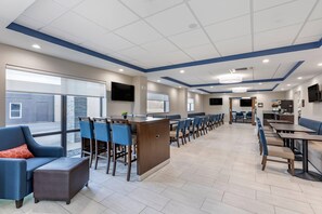 A spacious indoor area with a long counter, seating arrangements, and a kitchen area in the background. - Comfort Suites St. Louis - Sunset Hills (St. Louis)