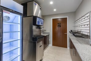 A kitchen with a stainless steel refrigerator, a water dispenser, and a freezer. There is a wooden door labeled 'Employees Only' and a wall-mounted rack with hooks. - Comfort Suites St. Louis - Sunset Hills (St. Louis)