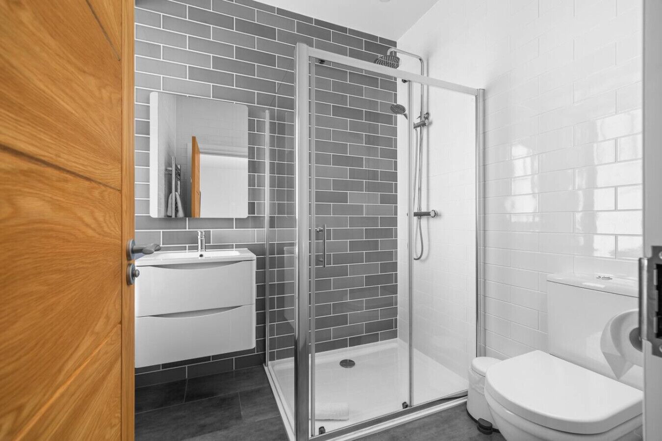 A modern bathroom with a glass shower enclosure, a white sink, and a toilet.
