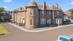 A two-story stone building with a turret and a chimney. - Panmure Apartment - golf course views (Monifieth)