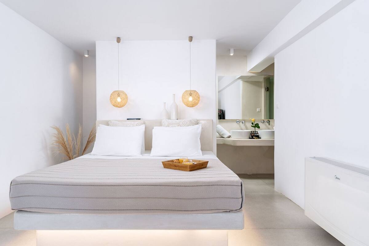 A modern bedroom with a large bed, bedside tables, and a bathroom visible in the background.
