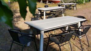 An outdoor dining area with a table and chairs, a boat in the background, and a wooden structure. - Stunning 2-bed Apartment in Kotka. Sauna Facility (Kotka)