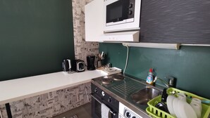 A compact kitchen with a microwave, toaster, coffee maker, and a green dish rack. - Stunning 2-bed Apartment in Kotka. Sauna Facility (Kotka)