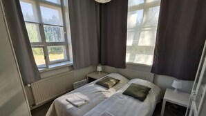 A double room with two beds, a window, a radiator, and a bedside table with a lamp. - Stunning 2-bed Apartment in Kotka. Sauna Facility (Kotka)