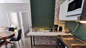 A compact kitchen with a microwave, coffee maker, and toaster. There is a dining area with a table and chairs. - Stunning 2-bed Apartment in Kotka. Sauna Facility (Kotka)