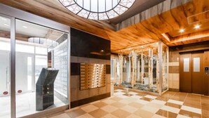 Un moderno vestíbulo con piso a cuadros, paredes de vidrio, techo de madera y un ascensor.