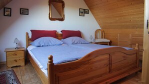 A bedroom with a wooden bed, two nightstands, a mirror, and a red and blue bedspread. - HAuszeit Kapitänshaus Friedrichsschleuse - Temporary home (Wittmund)