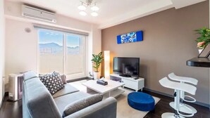 A modern living room with a sofa, a coffee table, a TV, and a plant. - Edifice (Sapporo)