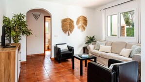 Un salon moderne avec un canapé, une table basse et un fauteuil en cuir noir. On y trouve également un meuble en bois et une plante en pot.