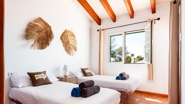 Une chambre d’hôtel avec deux lits, une fenêtre avec des rideaux et une vue sur les arbres à l’extérieur.