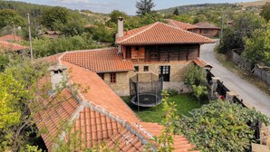 A traditional house with a tiled roof, a stone chimney, and a small garden with a trampoline. - Rent-a-villa with outdoor jacuzzi, BBQ, trampoline and indoor infrared sauna (Medven)