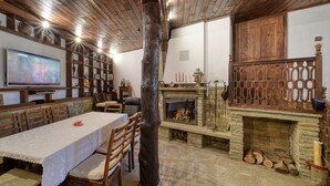 A cozy room with a stone fireplace, wooden furniture, and a television on a wall. - Rent-a-villa with outdoor jacuzzi, BBQ, trampoline and indoor infrared sauna (Medven)