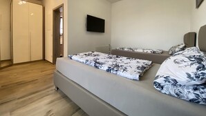 A bedroom with a bed, a TV mounted on the wall, and a wardrobe. - Holiday apartment “Hans” (WA324) (Wackersdorf)