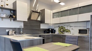 A modern kitchen with a central island, built-in appliances, and a dining area with a table and chairs. - Holiday apartment “Hans” (WA324) (Wackersdorf)