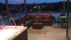 A rooftop terrace with a hot tub, a sofa, and a dining table. - Holiday apartment “Hans” (WA324) (Wackersdorf)