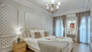 Une chambre spacieuse avec un grand lit, une table de chevet, un lustre et une vue sur l’extérieur par la fenêtre.
