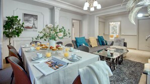 Un salon moderne avec un coin repas, comprenant un ensemble de canapés, une table basse et une table à manger avec des éléments pour le petit-déjeuner.