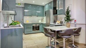 Une cuisine moderne avec des armoires de couleur turquoise, un évier en acier inoxydable et un coin repas équipé de tabourets de bar.