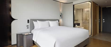 Ein modernes Hotelzimmer mit einem großen Bett, Nachttischen, einer großzügigen Dusche und Holzboden.