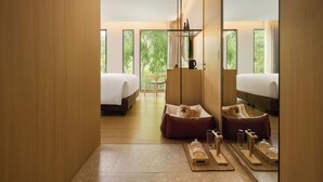 Una habitación de hotel moderna con dos camas, piso de madera, un ventanal grande y una zona de estar acogedora.