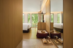 Una habitación de hotel moderna con dos camas, piso de madera, un ventanal grande y una zona de estar acogedora.