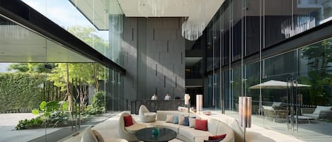 Un espacio interior moderno con una zona de estar circular, ventanas amplias y una lámpara colgante.
