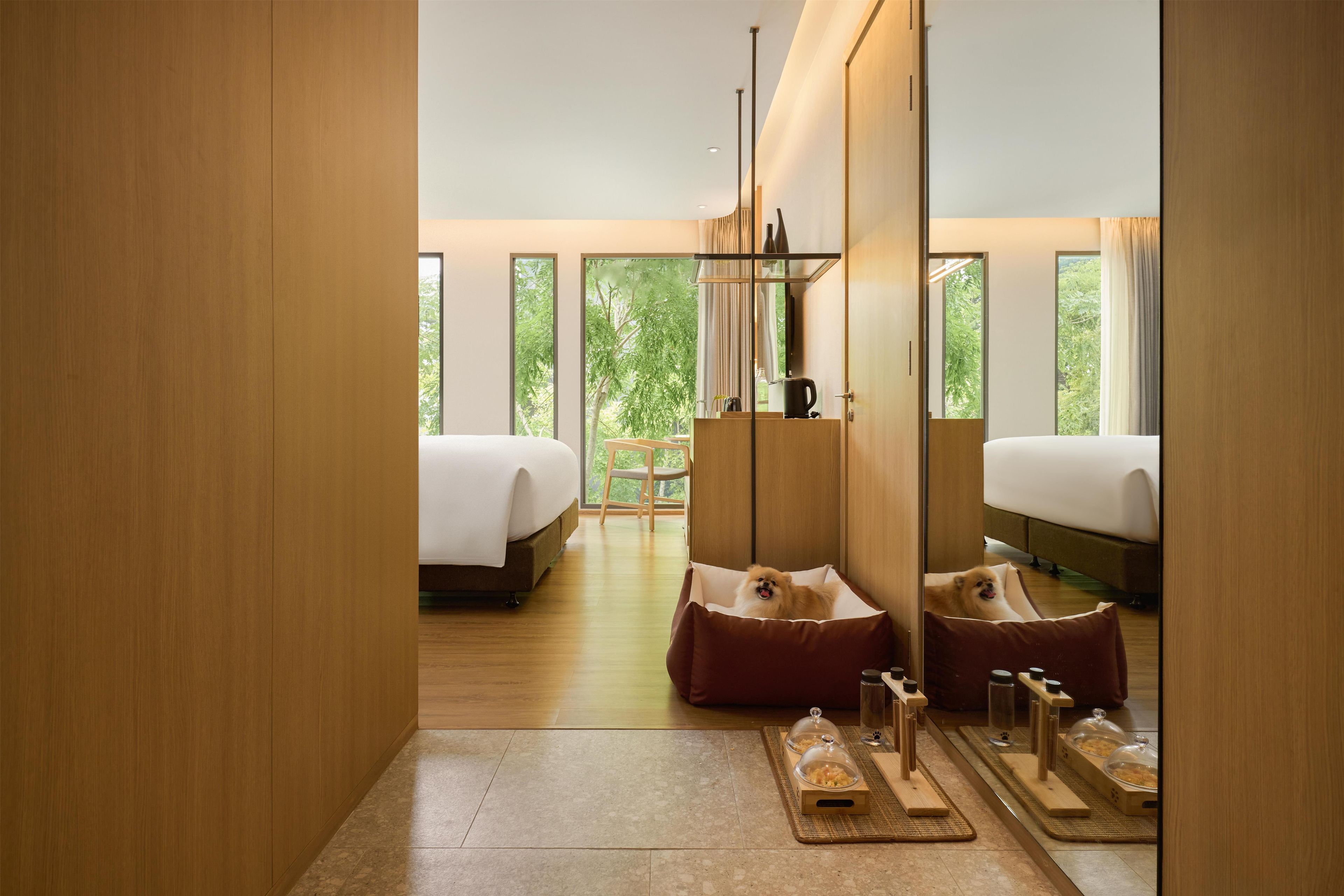 Ein modernes Hotelzimmer mit zwei Betten, einer Sitzecke und einer Frühstückstheke.