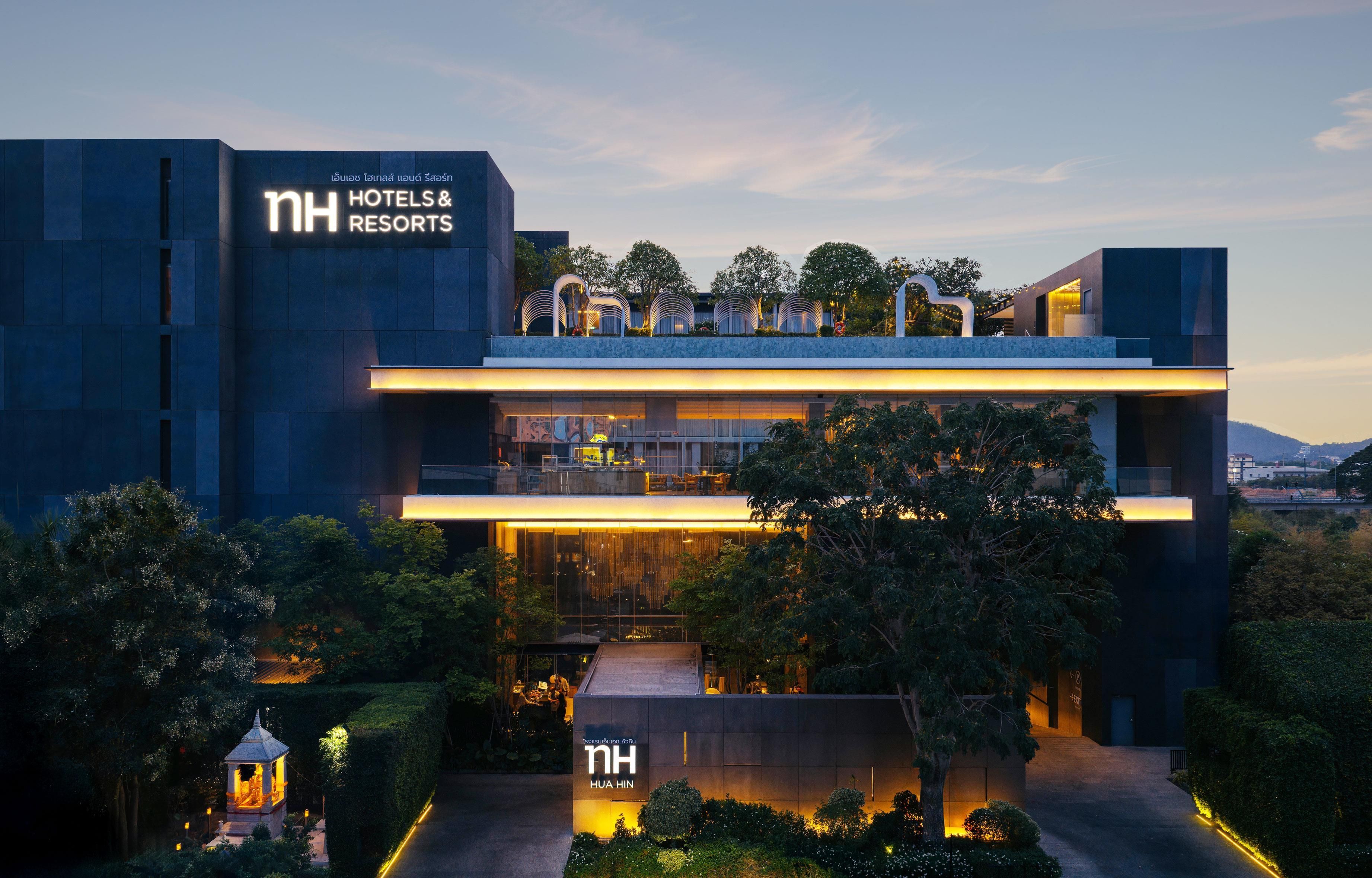 A modern hotel with a prominent sign for NH Hotels & Resorts.