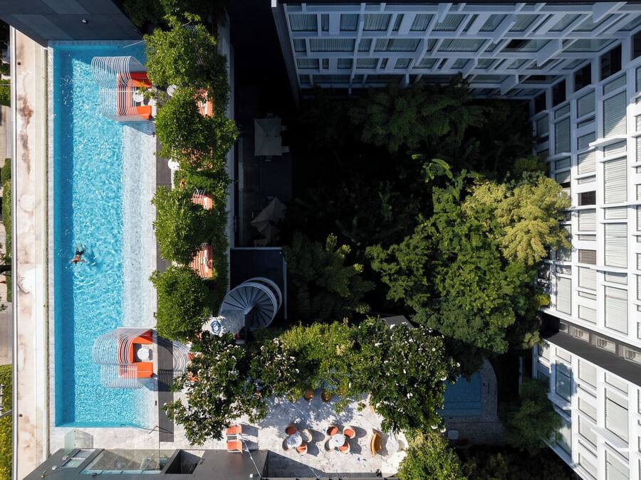 Ein Luftbild eines Hotels mit Schwimmbad, Sitzgelegenheiten im Freien und üppiger Bepflanzung.