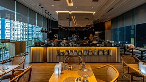 Un restaurante moderno con una barra central, mesas y sillas de madera.