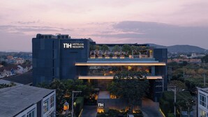 Un hotel moderno con un llamativo letrero de 'NH Hotels & Resorts', un jardín en la azotea y una entrada bien iluminada.