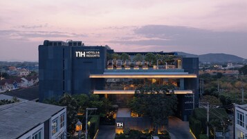 Un hotel moderno con un llamativo letrero de 'NH Hotels & Resorts', un jardín en la azotea y una entrada bien iluminada.