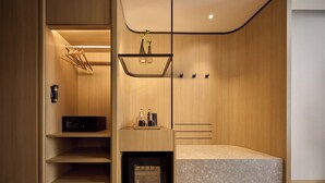 A modern, compact room with built-in storage, a small seating area, and a built-in heater. - NH Hua Hin (Hua Hin)