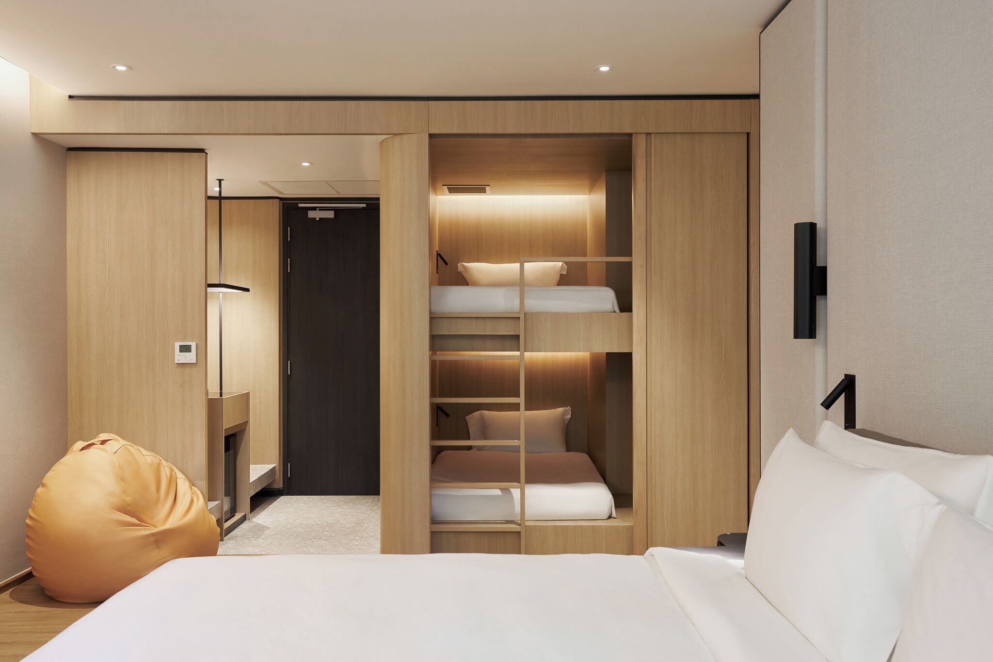 Ein modernes Hotelzimmer mit einem Bett, einer Sitzecke, einem Kleiderschrank und einem Schrank mit Regalen.