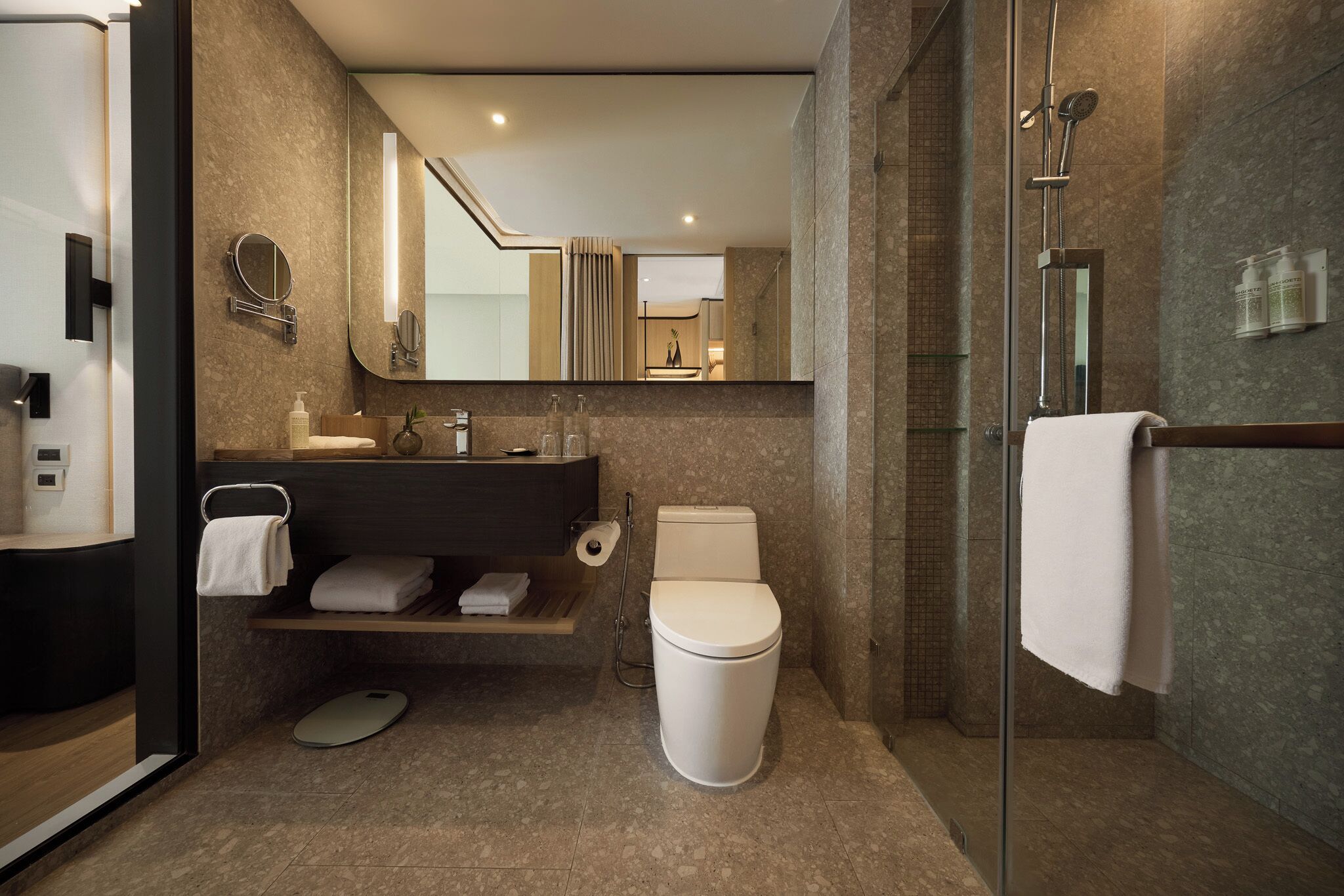 Une salle de bain moderne avec une douche à parois de verre, des toilettes, un lavabo avec un miroir et un porte-serviettes.