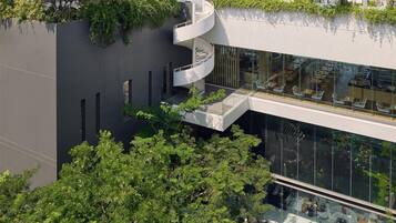A modern building with a rooftop garden, glass walls, and outdoor seating.