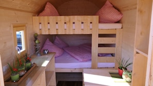 Une cabane en bois avec des lits superposés, une fenêtre et des plantes en pot.