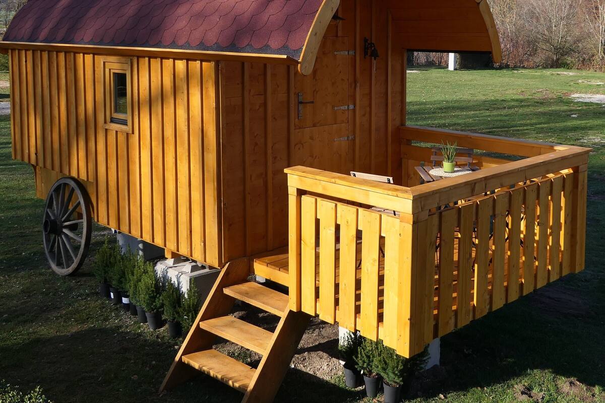 Une cabane en bois avec une véranda couverte et une petite table.