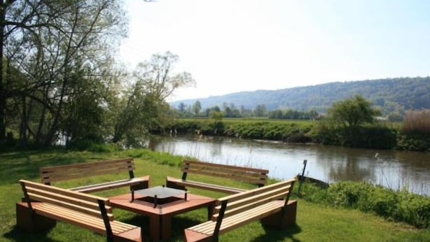 Un espace de pique-nique au bord de la rivière, équipé de bancs et d’une table.