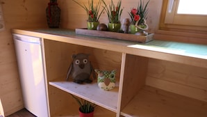 Une cuisine en bois dotée d’un réfrigérateur encastré, d’étagères ornées d’objets décoratifs et de plantes en pot.