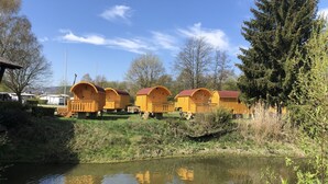 Une rangée de cabanes jaunes aux toits rouges, un étang avec des canards et un ciel bleu azur.