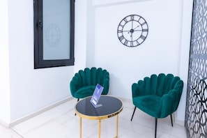A room with a round table, two chairs, a clock, and a door with a frosted glass panel. - Evita Asty (Athens)
