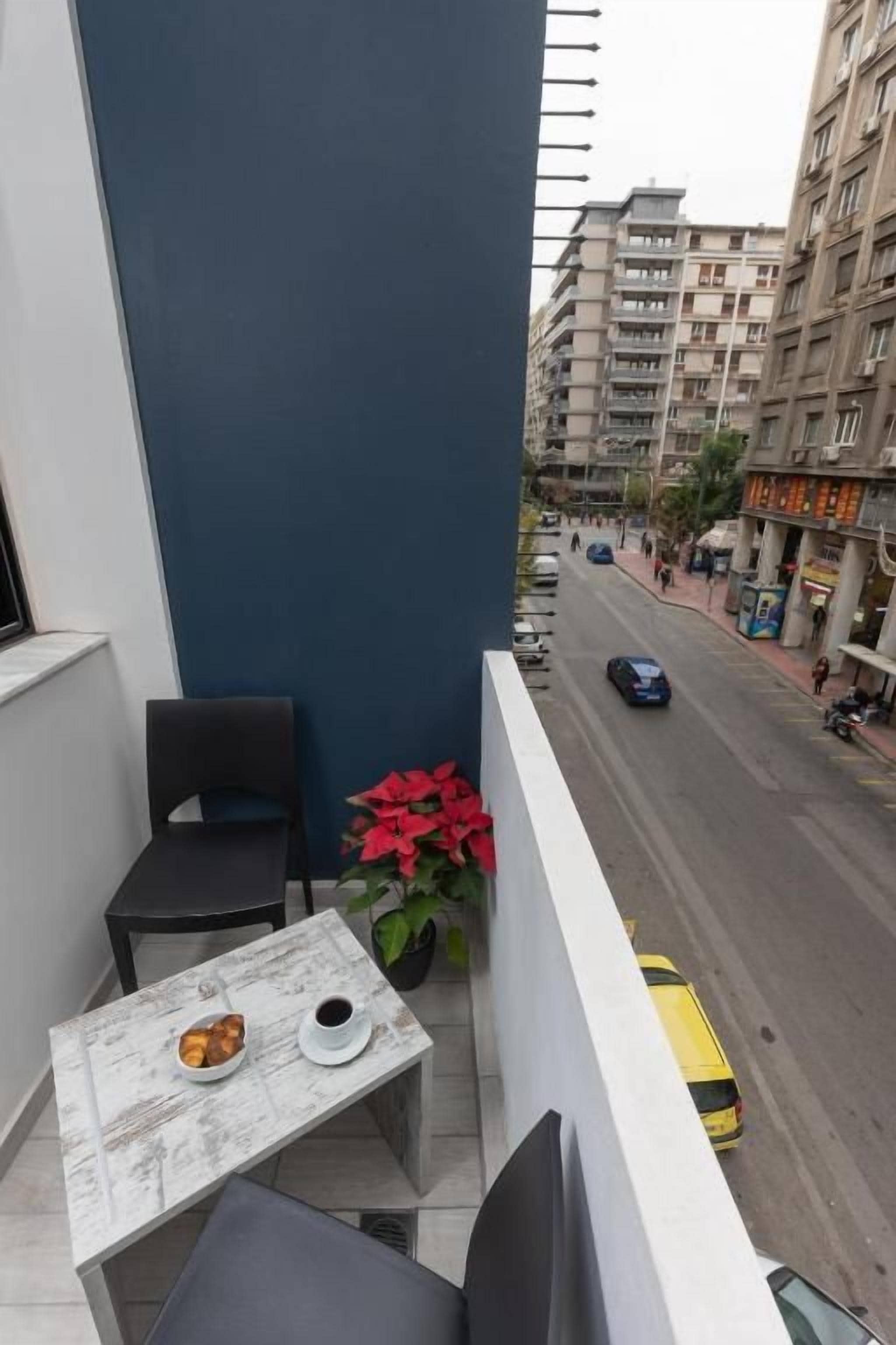 Ein Balkon mit Tisch, Stühlen und einer Topfpflanze.