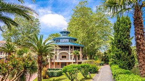 Un edificio de estilo tradicional con techo azul, rodeado de exuberante vegetación y palmeras.
