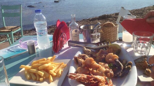 A table with seafood, fries, and drinks by a lakeside with chairs and a view of the water. - Villa Yason Private Heated Pool Within Easy Reach Of Beaches, Tavernas & Shops. (Ionian Islands)